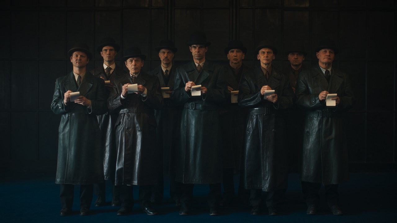 Präzise besetztes Ensemble in Ledermänteln am Filmset
